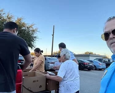 Reparto de alimentos y ayuda en un estacionamiento comunitario